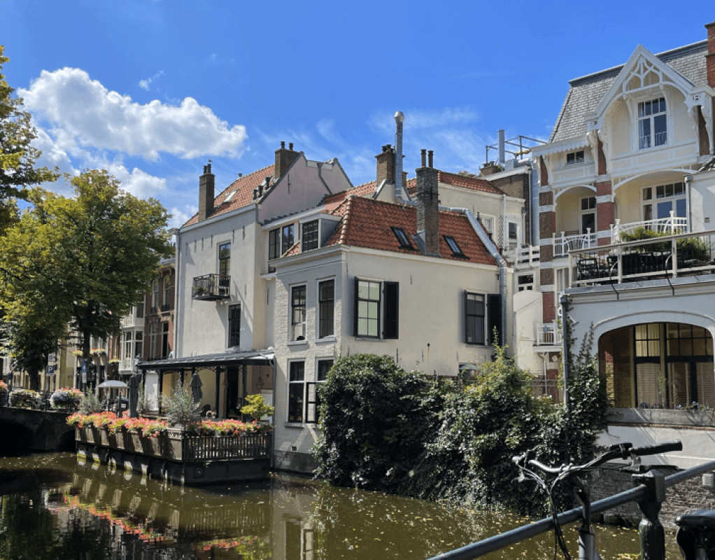 White houses next to a canal. The sky is blue with a few clouds.