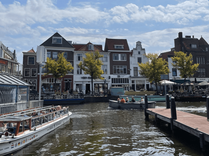 Houses with a canal with tourist boats in front