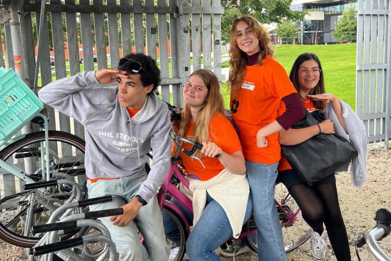 Students sitting on a bike together in a bike shed